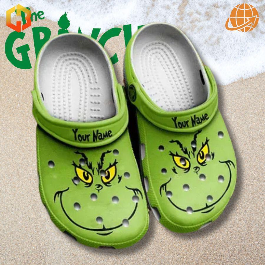 Custom Grinch Crocs Shoes displayed on a sandy beach with snow, showcasing their all-season appeal.