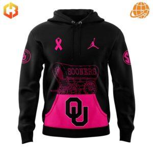 Front view of Oklahoma Sooners Breast Cancer Awareness Hoodie featuring pink ribbon, Jordan logo, and Sooners wagon design on black with pink pocket.