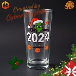 A festive beer glass featuring the Grinch in Clemson Tigers colors, holding a football and wearing a Santa hat, with 'Christmas 2024' text and tiger paw prints in the design