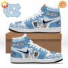 North Carolina Tar Heels themed Air Jordan 1 sneakers with blue and white color scheme and team graphics.