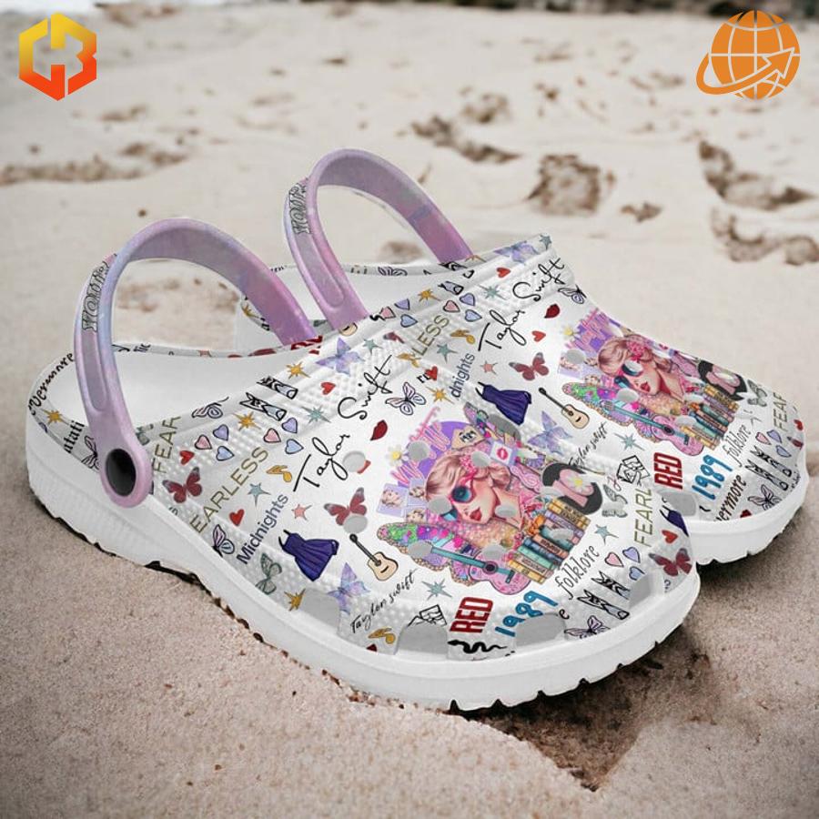 Taylor Swift inspired Crocs clogs with colorful design placed on beach sand.