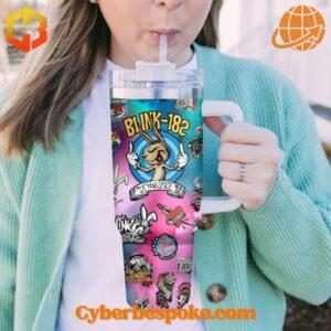 Person drinking from a colorful Blink-182 tumbler with straw